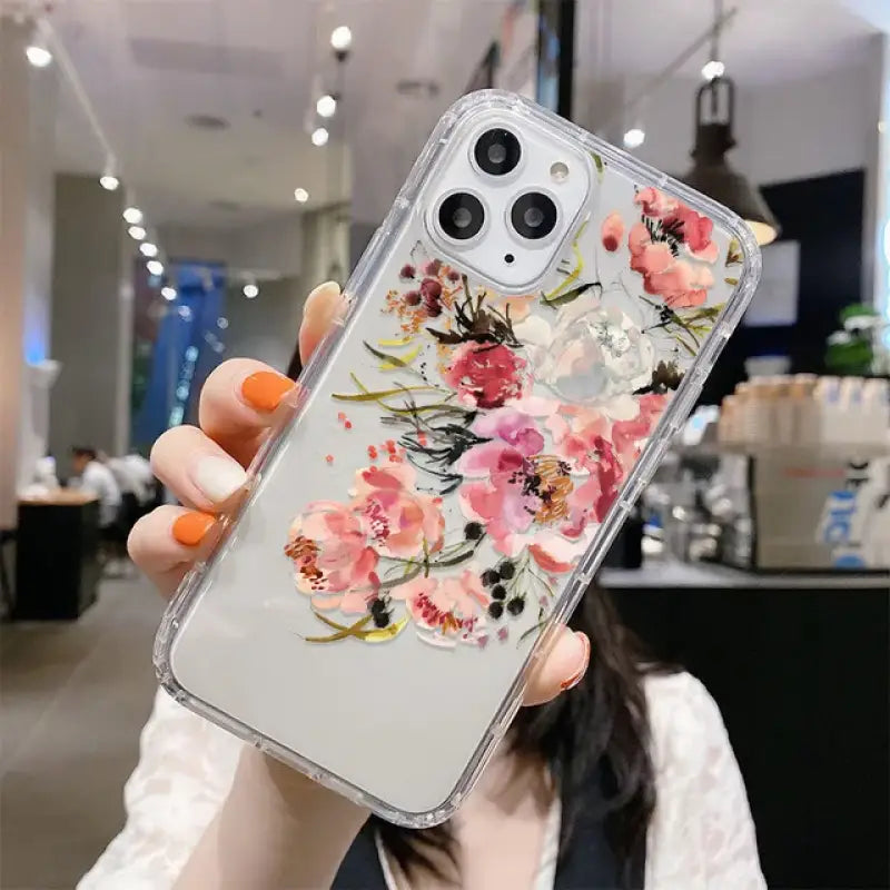 A woman holding up a phone case with flowers on it