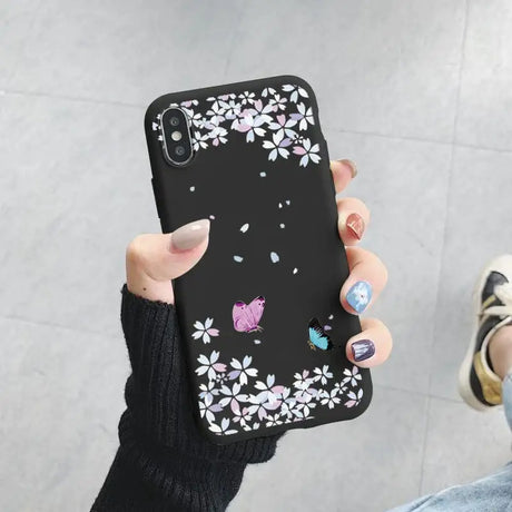 A woman holding a phone case with flowers and butterflies