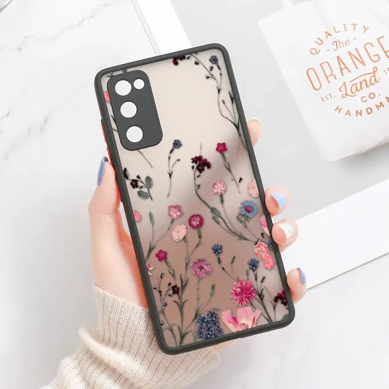 a woman holding a phone case with flowers on it