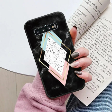 a woman holding a phone case with a geometric design