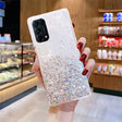 a woman holding a phone case with glitter