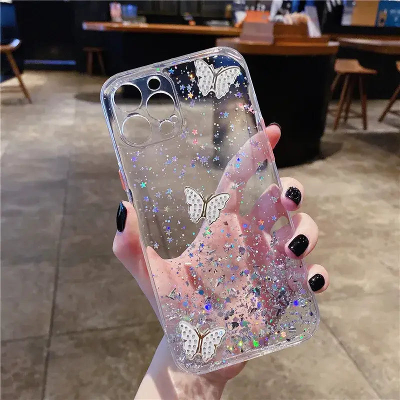 a woman holding a phone case with glitter and butterflies