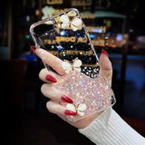 a woman holding a phone case with glitter butterflies