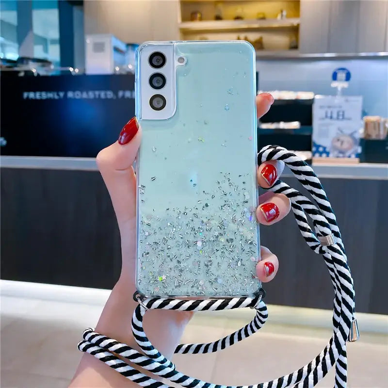 a woman holding a phone case with glitter and black and white stripes