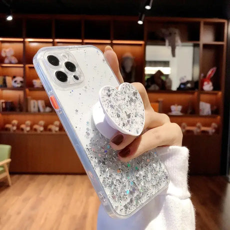 A woman holding a phone case with glitter on it