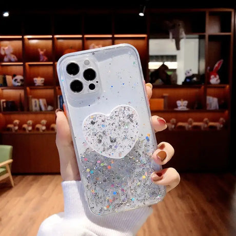 A woman holding a phone case with glitter hearts