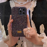 a woman holding a phone case with a gold and black glitter