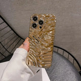 a woman holding a phone case with a gold swirl design