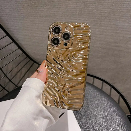 A woman holding a phone case with a gold swirl design