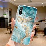 a woman holding up a phone case with a gold glitter on it