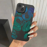 a woman holding a phone case with a green and blue pattern