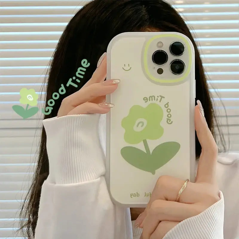 a woman holding up a phone case with a green heart