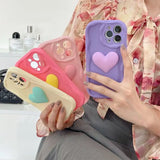 a woman holding a phone case with a heart on it