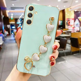 A woman holding a phone case with heart charms