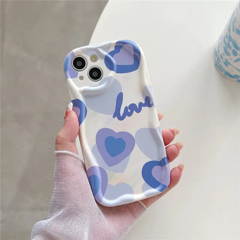 A woman holding a phone case with hearts on it