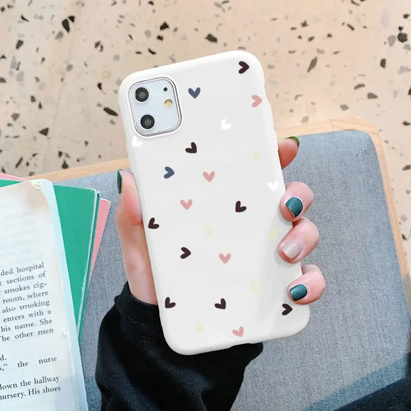 a woman holding a phone case with hearts on it