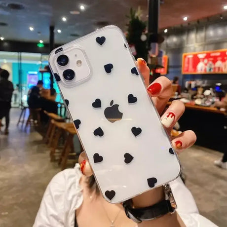 A woman holding up a phone case with hearts on it