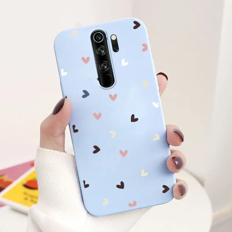 a woman holding a phone case with hearts on it