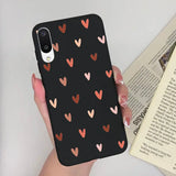 a woman holding a phone case with hearts on it
