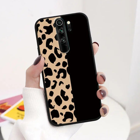 A woman holding a phone case with a leopard print