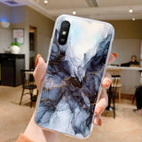 a woman holding up a phone case with a marble pattern