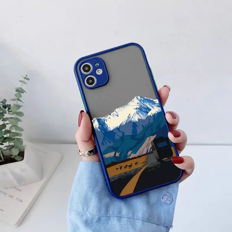 A woman holding a phone case with a mountain scene