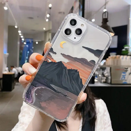 A woman holding up a phone case with a mountain scene