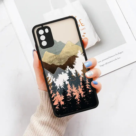 A woman holding a phone case with a mountain scene