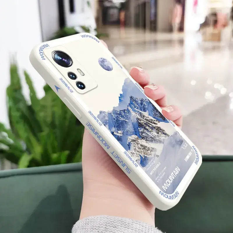 a woman holding a phone case with a mountain scene on it