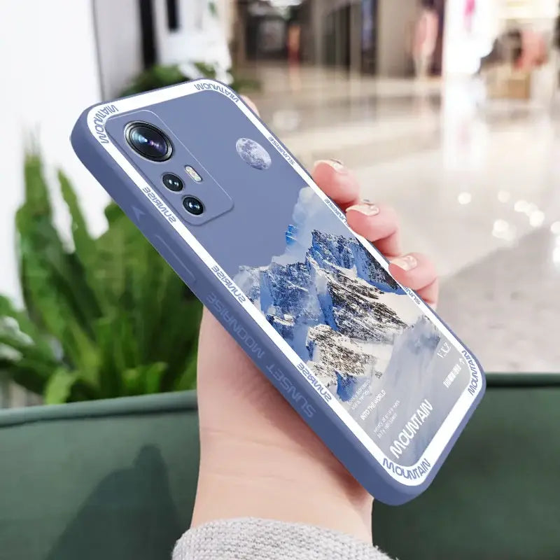 a woman holding a phone case with a mountain scene on it