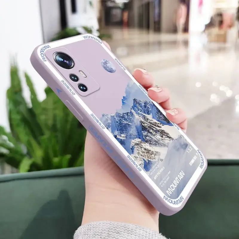 A woman holding a phone case with a mountain scene on it