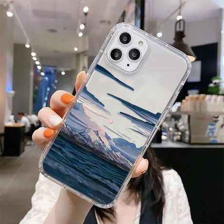 A woman holding up a phone case with a painting on it