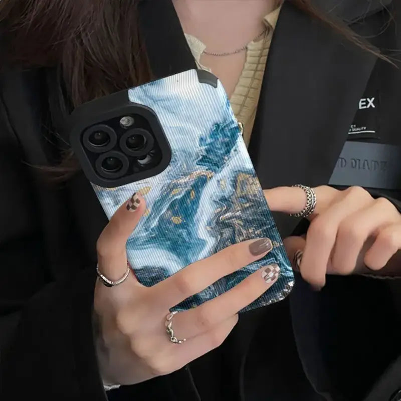 a woman holding a phone case with a painting on it
