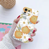 a woman holding a phone case with a pattern of oranges