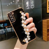 a woman holding a phone case with pearls