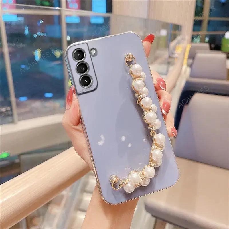 a woman holding a phone case with pearls and pearls