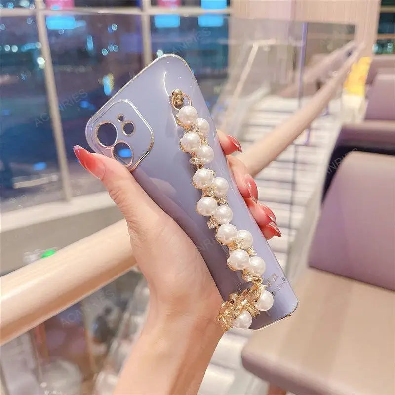 a woman holding a phone case with pearls and pearls