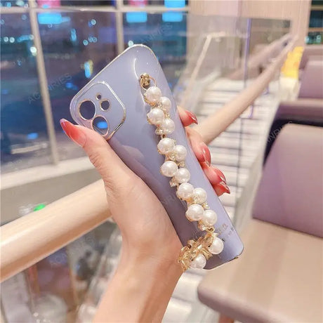 a woman holding a phone case with pearls and pearls