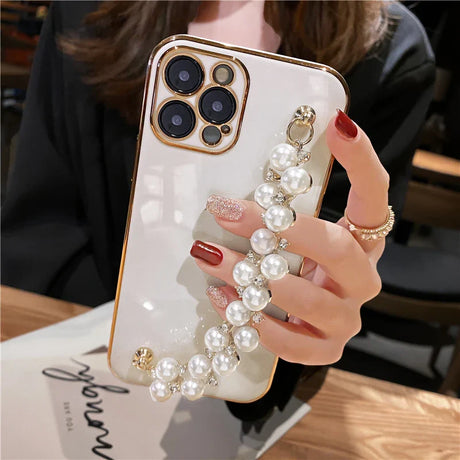 a woman holding a phone case with pearls and pearls