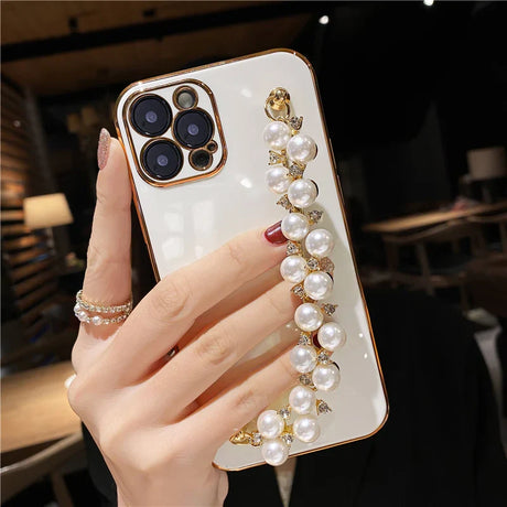 a woman holding a phone case with pearls and gold