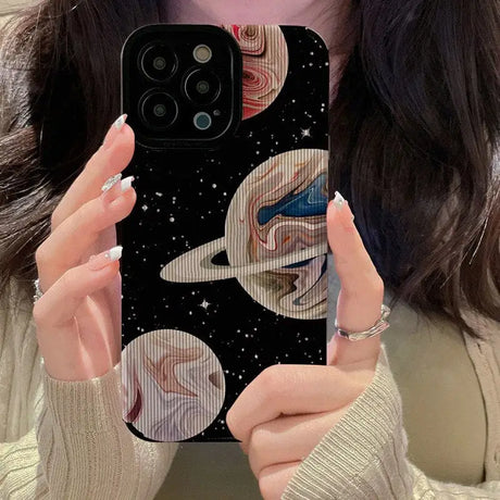 A woman holding up her phone case with a picture of the planets