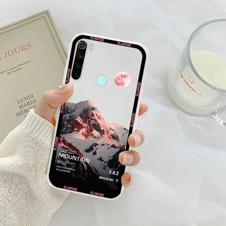 a woman holding a phone case with a pink sunset on it