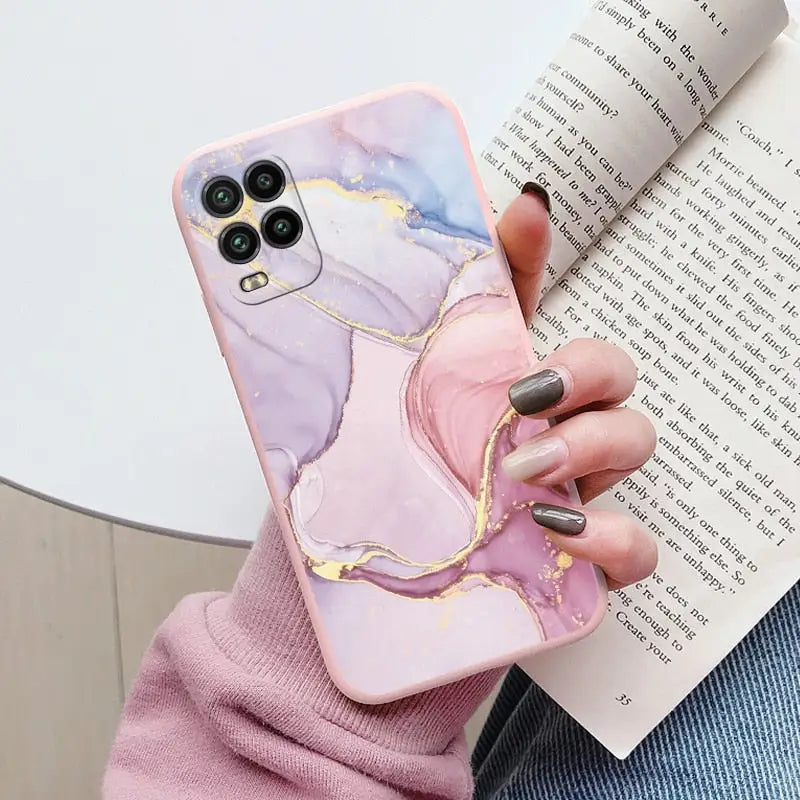 a woman holding a phone case with a pink marble pattern
