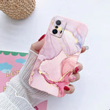 a woman holding a phone case with a pink marble pattern