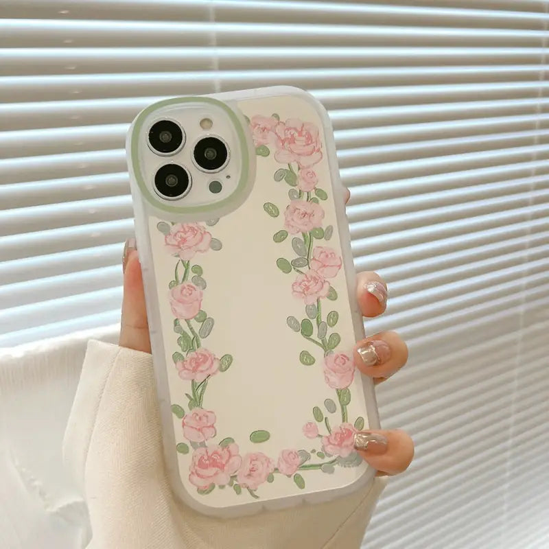 a woman holding a phone case with pink roses on it