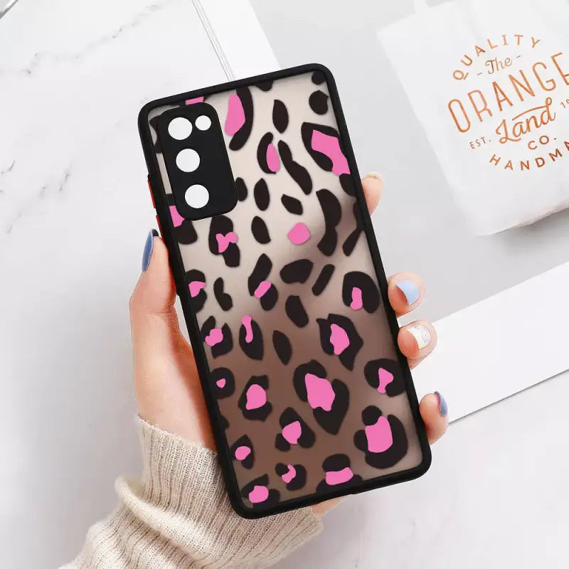 a woman holding a phone case with pink and black leopard print