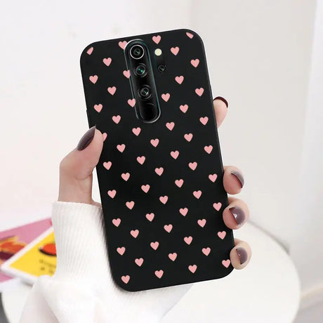 A woman holding a phone case with pink hearts on it