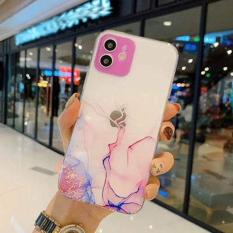 A woman holding up a phone case with a pink and blue marble design