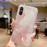 a woman holding a phone case with a pink marble pattern