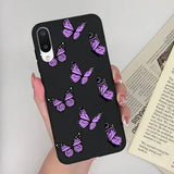 a woman holding a phone case with purple butterflies on it
